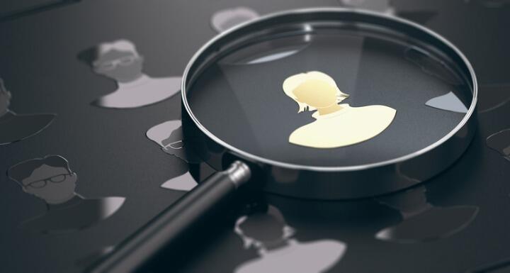 Magnifying glass showing close up of the silhouette of a head hunter or human resources coordinator