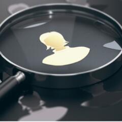 Magnifying glass showing close up of the silhouette of a head hunter or human resources coordinator