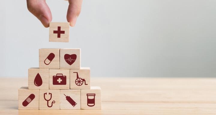 toy blocks with icons from health related disciplines arranged in a pyramid by an adult