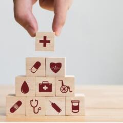 toy blocks with icons from health related disciplines arranged in a pyramid by an adult