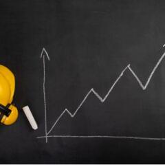 Helmet and rising construction stats on blackboard