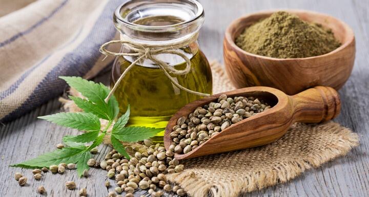 Hemp oil, seeds, and leaves arranged on a countertop 