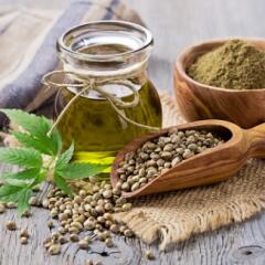 Hemp oil, seeds, and leaves arranged on a countertop 