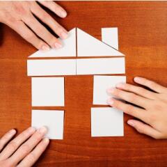 3 hands putting together puzzle shaped as a house