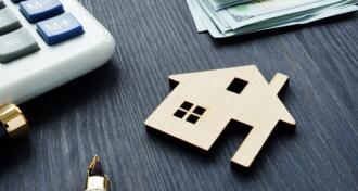 House vale concept with wooden house on table with calculator, money, and pen