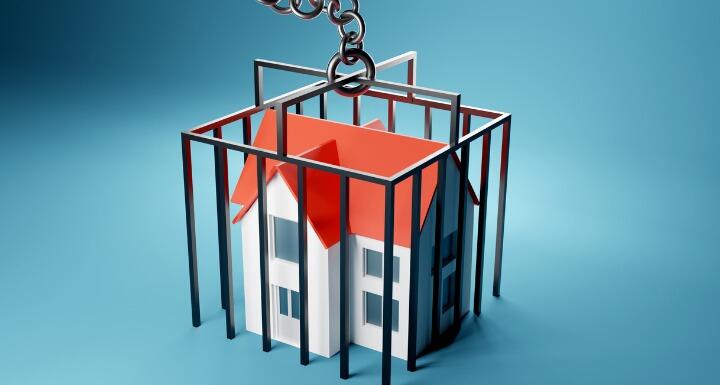 A toy house in a black cage on a blue background