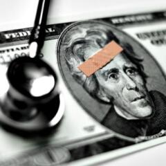 A twenty dollar bill with a band aid on Andrew Jackson's forehead and a stethoscope on the bill