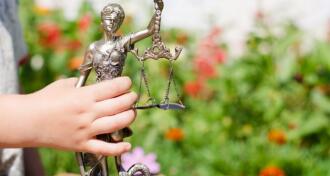 Kid's hand holding sculpture of themis