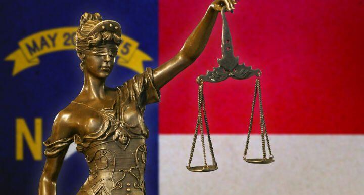 Lady Justice before a flag of North Carolina