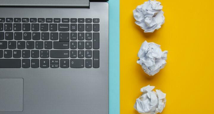 Laptop keyboard next to crumpled paper balls