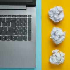 Laptop keyboard next to crumpled paper balls