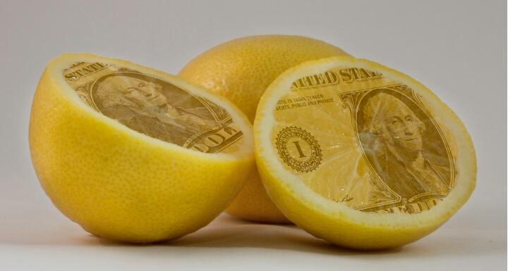 Lemons cut in half and the insides are the face of a dollar bill