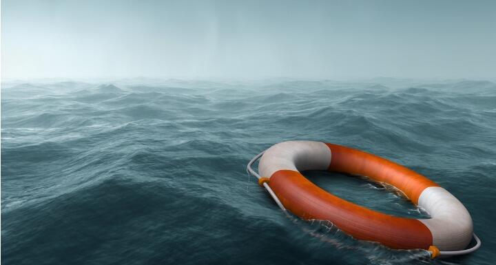 An orange and white life preserver floating on scary dark seas