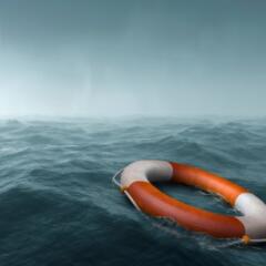 An orange and white life preserver floating on scary dark seas