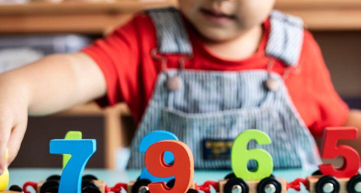 Little boy playing mathematics wooden toy at nursery