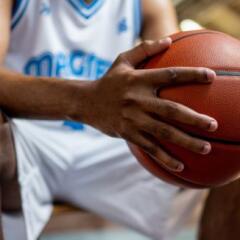 Male basketball player holding ball while sitting on bench