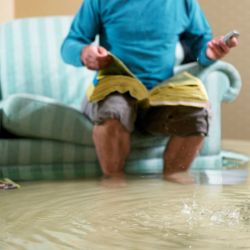 Man sitting in flooded living room using phone-Color Icon