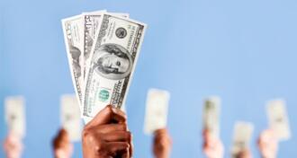 Many hands holding up US dollars