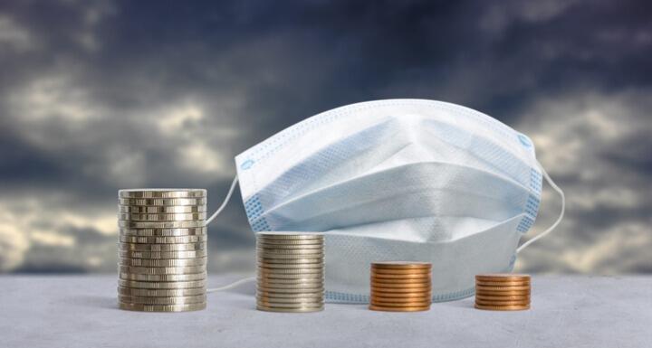 stacks of coins in front of a medical mask