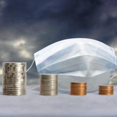 stacks of coins in front of a medical mask