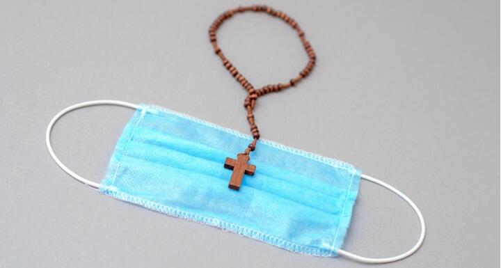 Wooden rosary with cross on medical mask