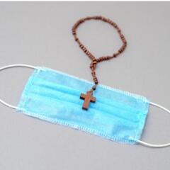Wooden rosary with cross on medical mask