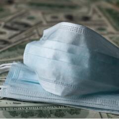 Medical facemask on top of one hundred dollar bills