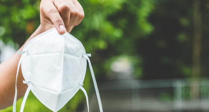 Person holding medical mask while outdoors