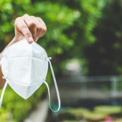 Person holding medical mask while outdoors