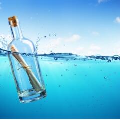 Message in a bottle floating in clear blue water with a clear blue sky in the background