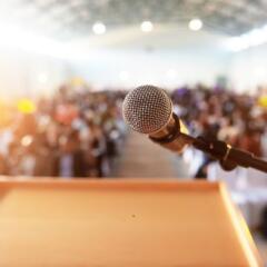 Microphone in front of podium with crowd in the background