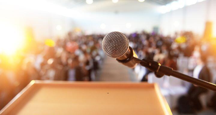 Microphone in front of podium with crowd in the background