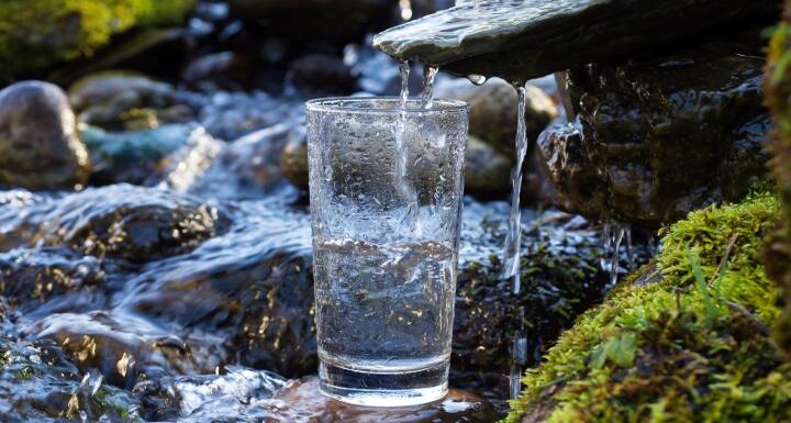 Freshwater from stream pouring into water glass
