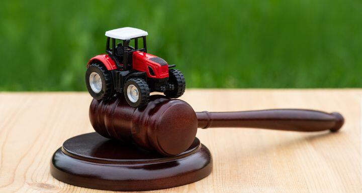 Miniature symbolic tractor and judge's gavel on a grass background