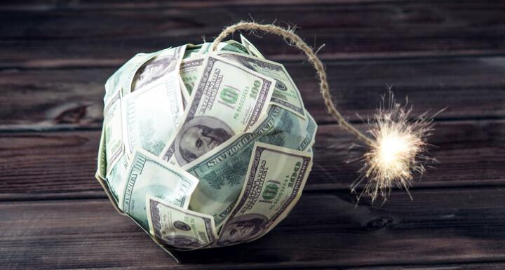 Ball of paper money shaped like a bomb with a rope as a fuse that is lit