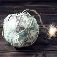 Ball of paper money shaped like a bomb with a rope as a fuse that is lit