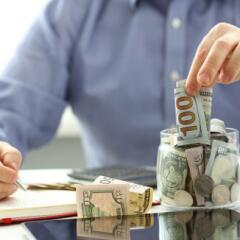 Man putting money in a jar while writing notes