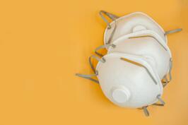 several N-95 personal protective masks on a yellow background