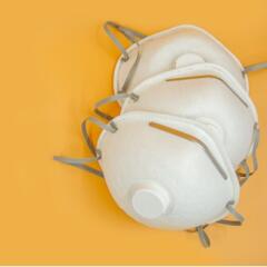 several N-95 personal protective masks on a yellow background