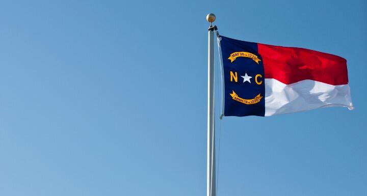 the North Carolina flag flying against a blue sky