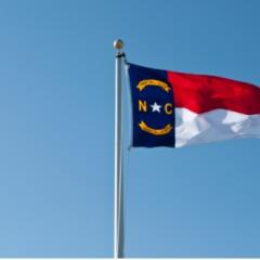 the North Carolina flag flying against a blue sky