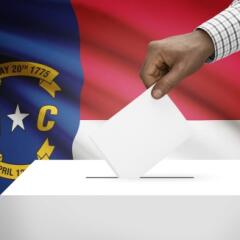A ballot box with the North Carolina flag in the background