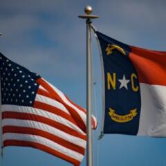 American and North Carolina flags waving in the wind