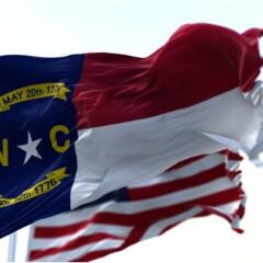 North Carolina state and American flag waving in the wind