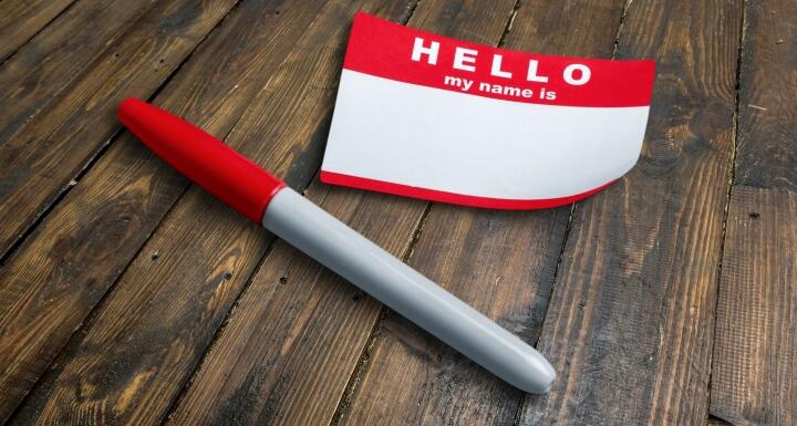 Blank nametag and pen on a wooden desk