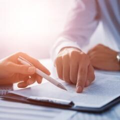 two people pointing at a document on a desk during a negotiation