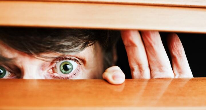 A neighbor's eyes peeking through horizontal blinds