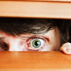 A neighbor's eyes peeking through horizontal blinds