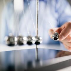 Man holding a ball of a Newton's Cradle