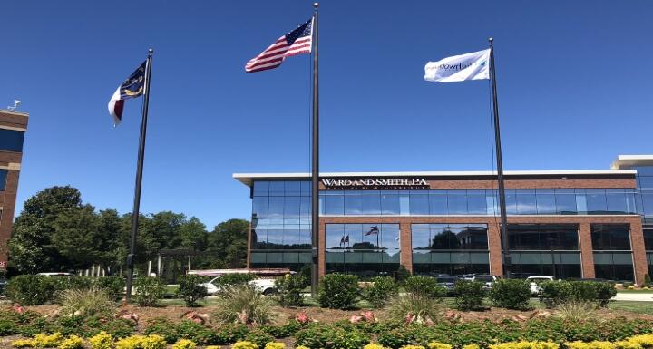 Outside Shot of Ward and Smith's Raleigh Office with Flags flying in front of building with blue skies